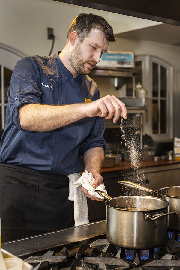 Restaurant Chef Cooking kitchen sprinkling salt seasoning into pot. Branding restaurant photography in Minneapolis. photographer food