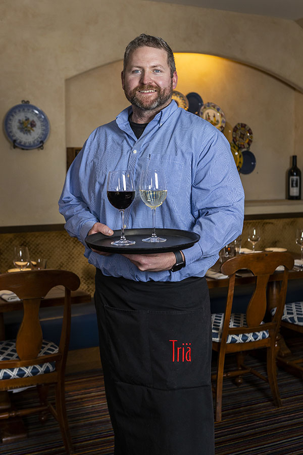 Waiter commercial portrait holding two glasses of wine, one red, one white in a restaurants dining room. food product photography