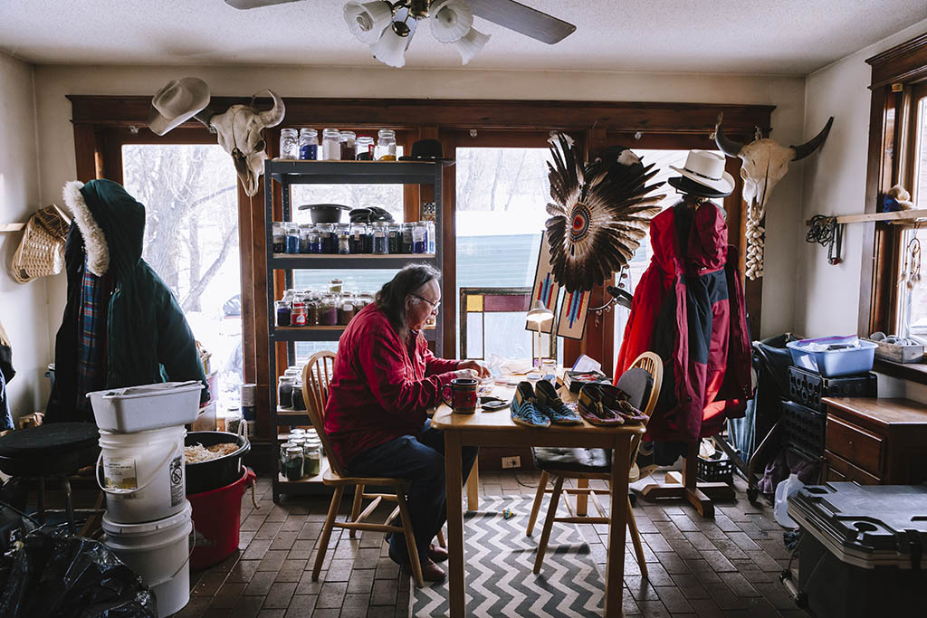 Editorial portrait of Dakota elder working on hand making Native American moccasins