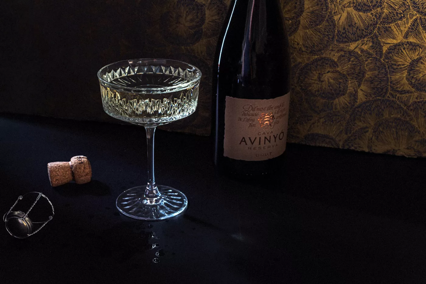 Avinyo bottle with an art deco glass full of champagne. Dark dramatic natural light. Chicago drink photographer
