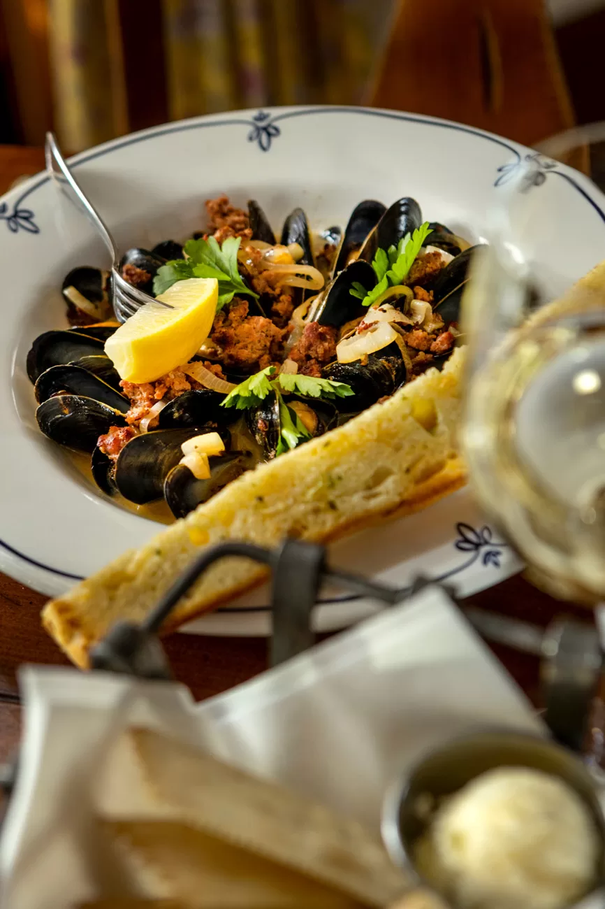 Mussels Lifestyle dinner plate with glass of white wine Chardonnay garlic bread crackers and butter Lifestyle food photography