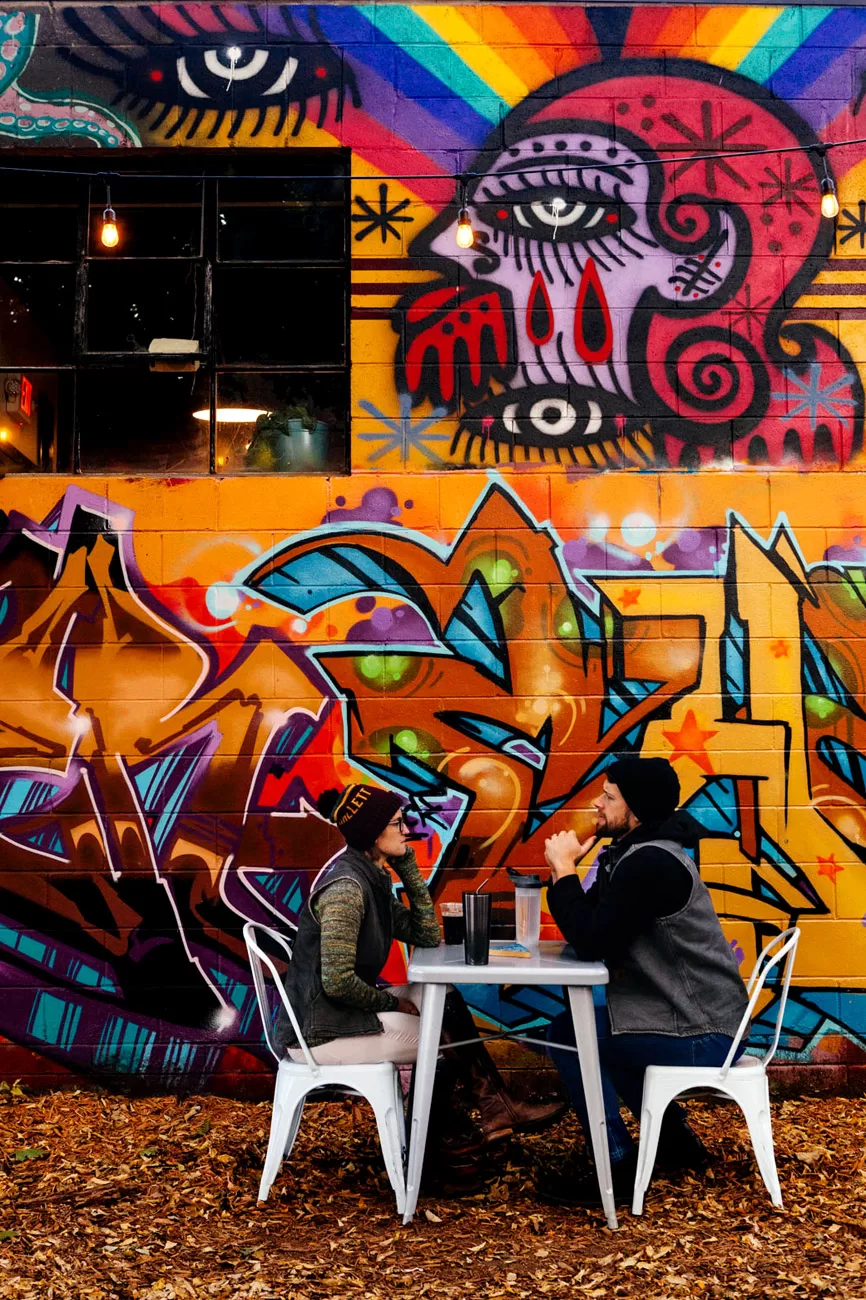 Two people sit outside at Reverie Restaurant Outdoor Patio graffiti wall in Minneapolis, Chicago editorial photographer